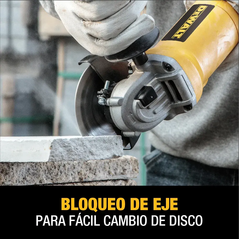 Primer plano de una persona utilizando una amoladora angular amarilla DEWALT para cortar piedra. La imagen destaca la función de bloqueo de eje para fácil cambio de disco, como lo indica el texto en español.