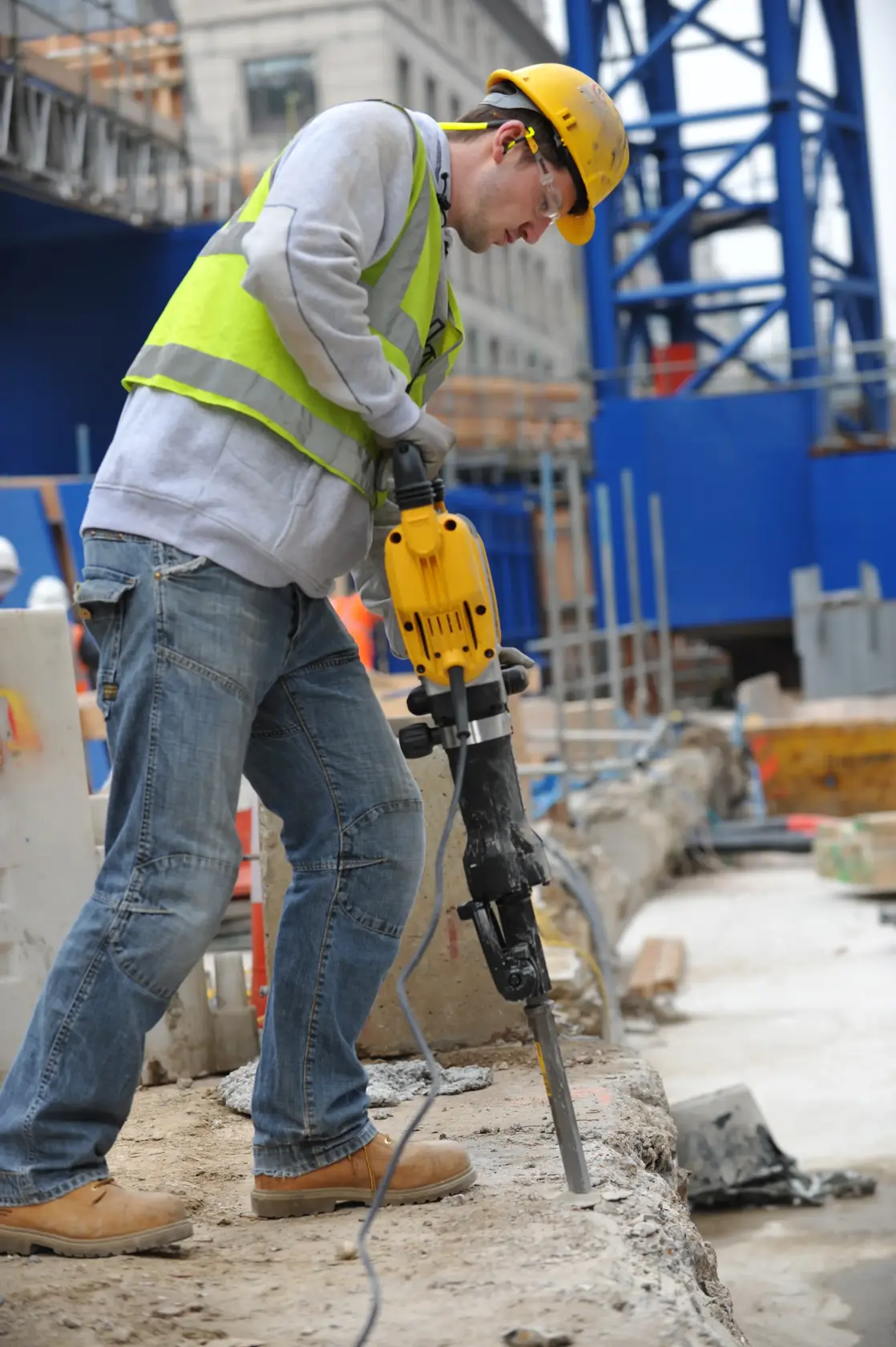 Trabajador usa el DEWALT D25960K martillo demoledor en concreto, obra, con equipo de seguridad.