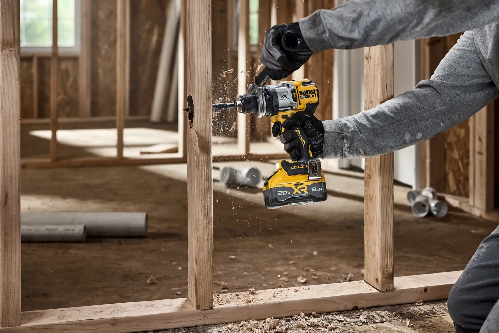 Persona usa taladro inalámbrico DEWALT para perforar un marco de madera en obra en construcción.