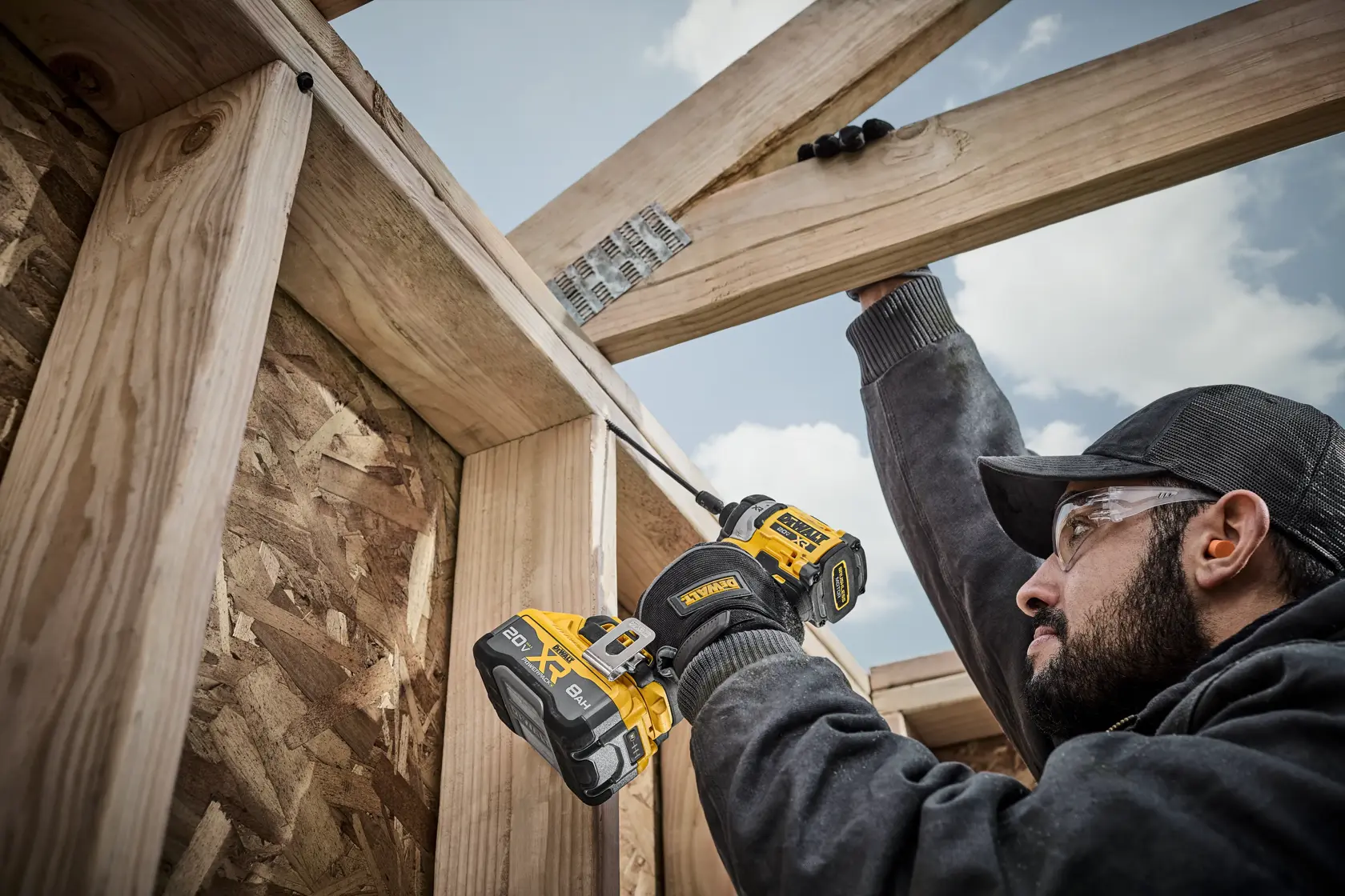 Persona usando destornillador de impacto DEWALT inalámbrico para atornillar vigas de madera en construcción.