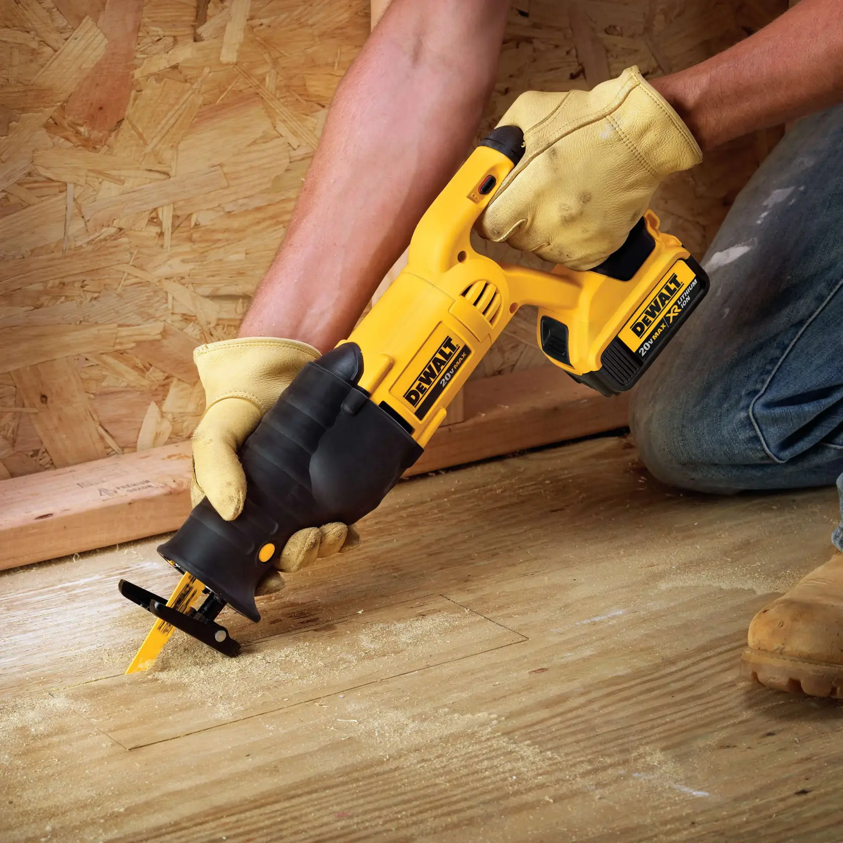 Uma pessoa com luvas de trabalho usa uma serra alternativa sem fio DEWALT para cortar o piso de madeira. A serra é amarela e preta, e há serragem visível ao redor da área de corte.